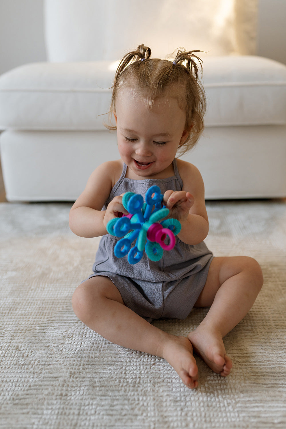 Child playing with Okee Toy. A colorful toy on a carpeted floor.