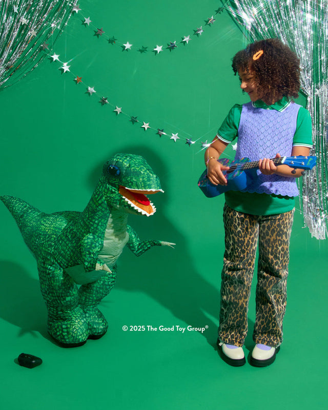 Child playing with a toy guitar next Inflatable Dinosaur RC Green on a green background