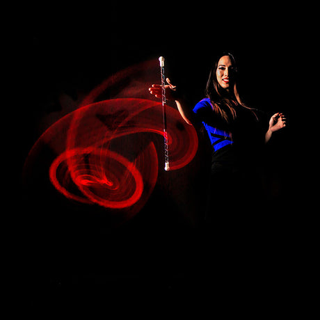 Woman holding a Wandini Glow.0 Magic LED Levitation Wand with red and blue light trails against a black background