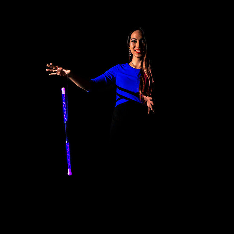 Woman holding a purple Wandini Glow.0 Magic LED Levitation Wand against a black background