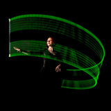 Person holding a glowing green Wandini Glow.0 Magic LED Levitation Wand against a black background