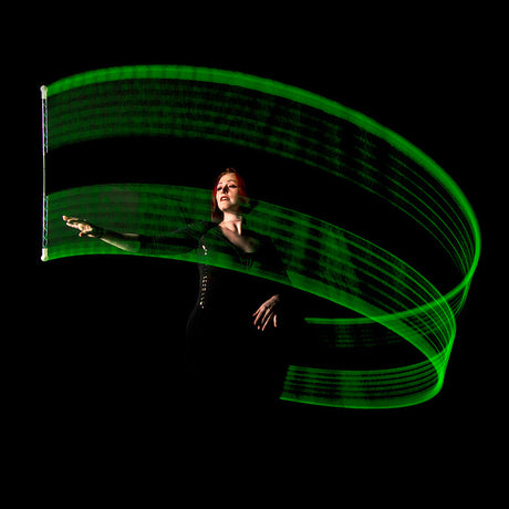 Person holding a glowing green Wandini Glow.0 Magic LED Levitation Wand against a black background