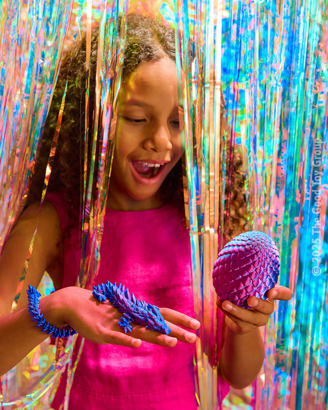 Child holding purple Twiddle Sensory Dragon! in front of colorful tinsel
