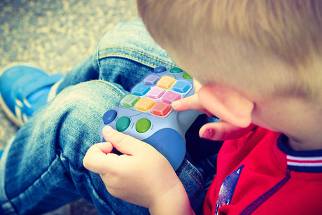 Child playing with a colorful Whack Attack On-The-Go Game toy on a blurred background