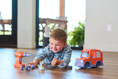 Child playing with toy Bluey Build-A-Buddy Motorized Car and Drill on a wooden floor