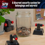 Glass jar with coins on a desk with Spy Labs: Invisible Tripwire Alarm around jar, branded 'Spy Labs'.