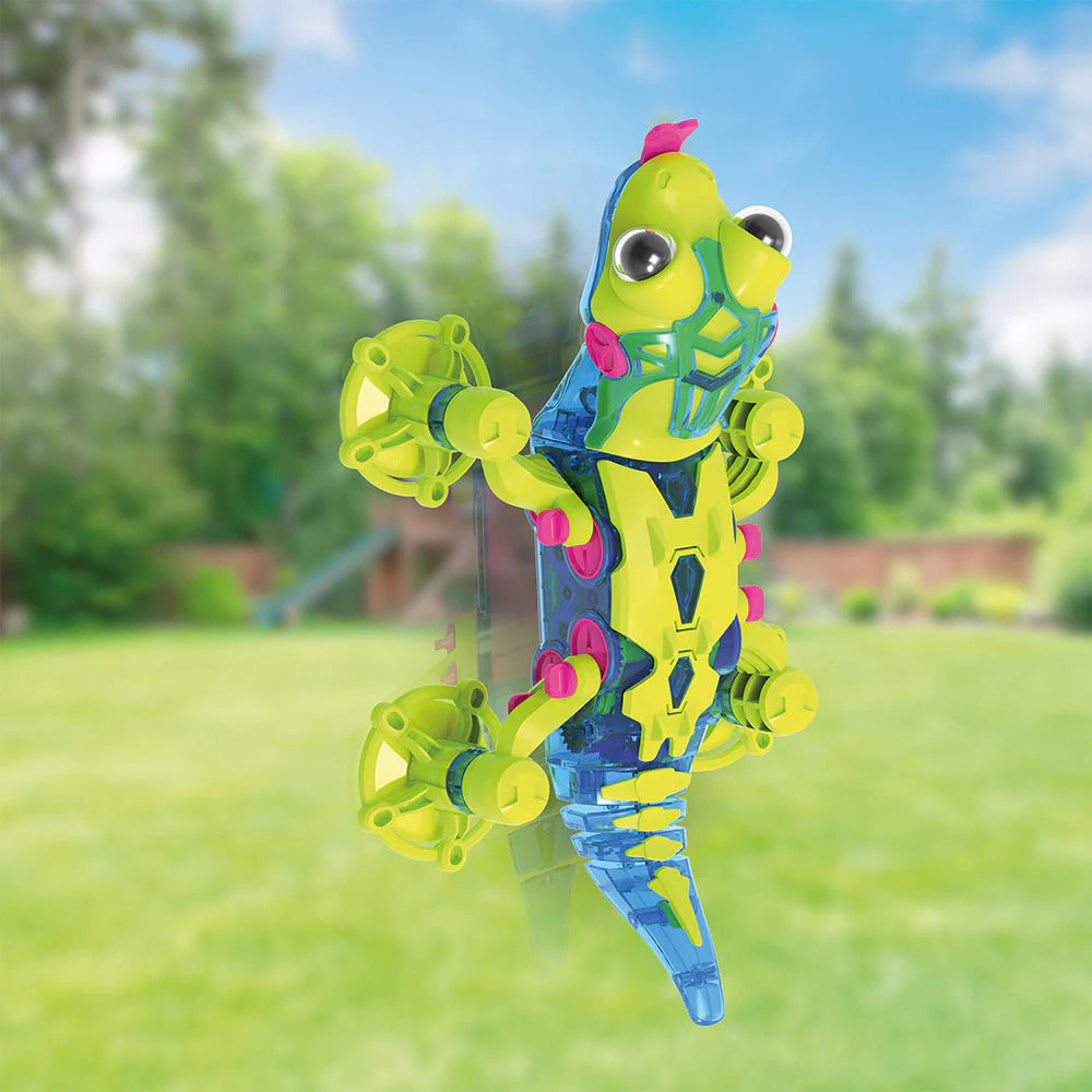 Colorful toy Geckobot 2.0 on a window with background with trees