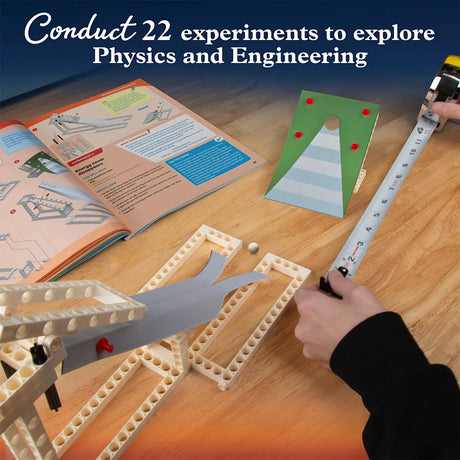Science experiment setup with a book, ruler, and small ball on a wooden surface.