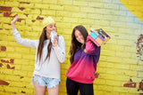 Two people posing against a yellow brick wall with colorful boom box and a Silver Bling Karaoke Microphone.