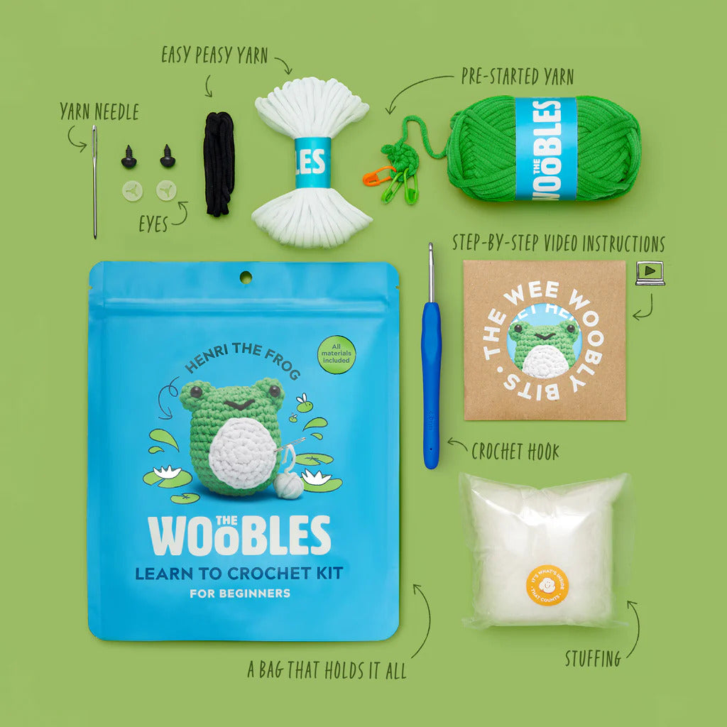 Woobles Henri the Frog Crochet Kit for beginners with all necessary materials on a green background